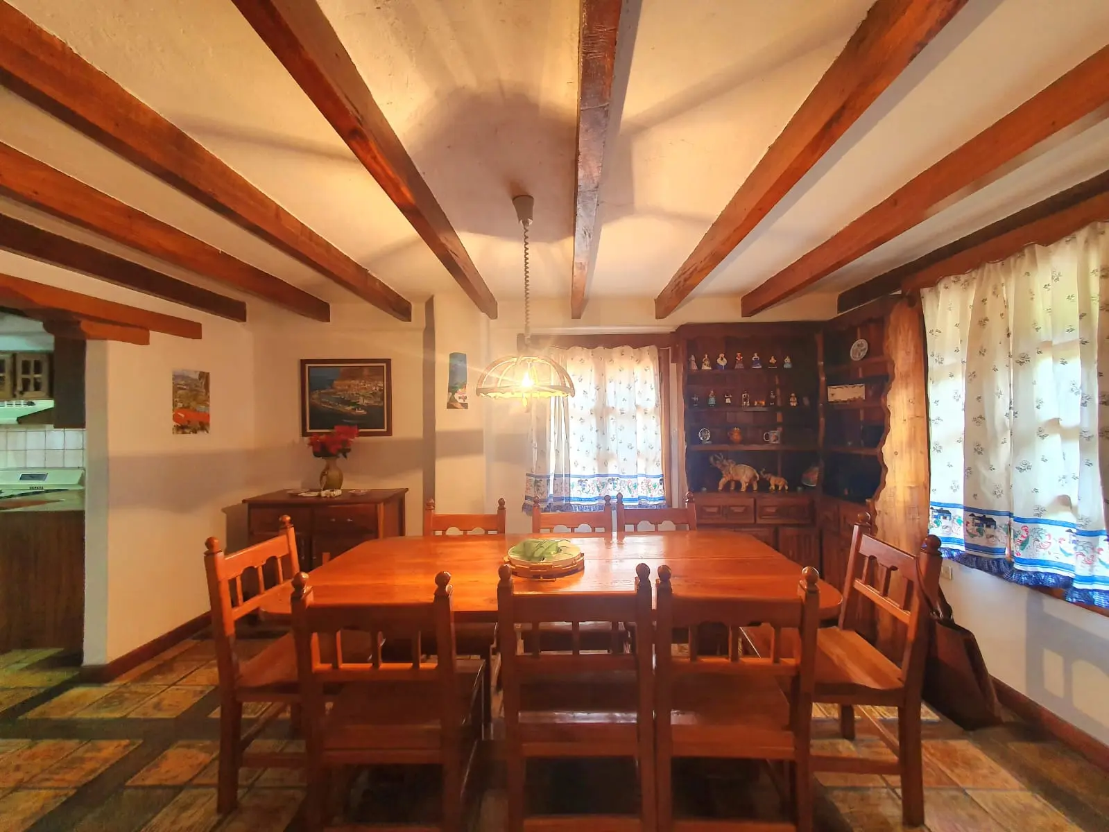"Comedor acogedor con muebles de madera artesanal y dos grandes ventanales con luz natural."